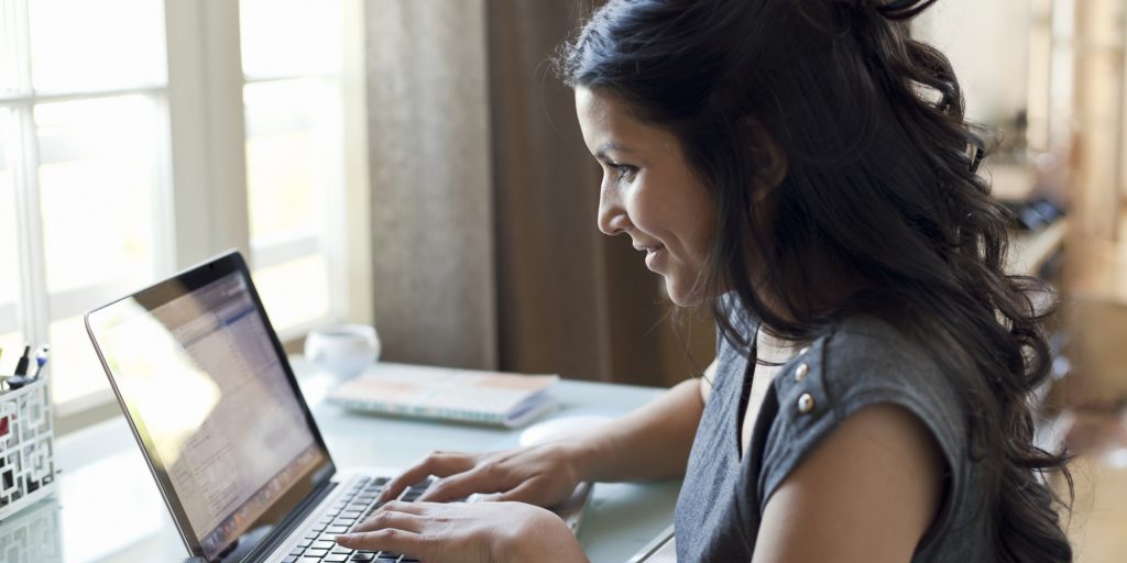 Woman working on laptop by window