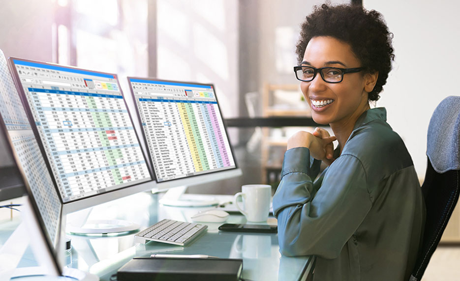 Woman sitting at a desk with two computer monitors open